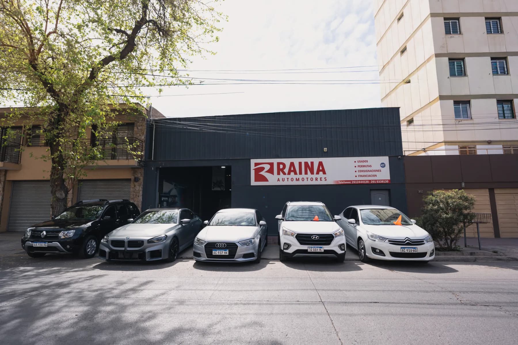 Frente de la sucursal de Raina Automotores en 25 de Mayo 727, Godoy Cruz, con autos usados en exhibición