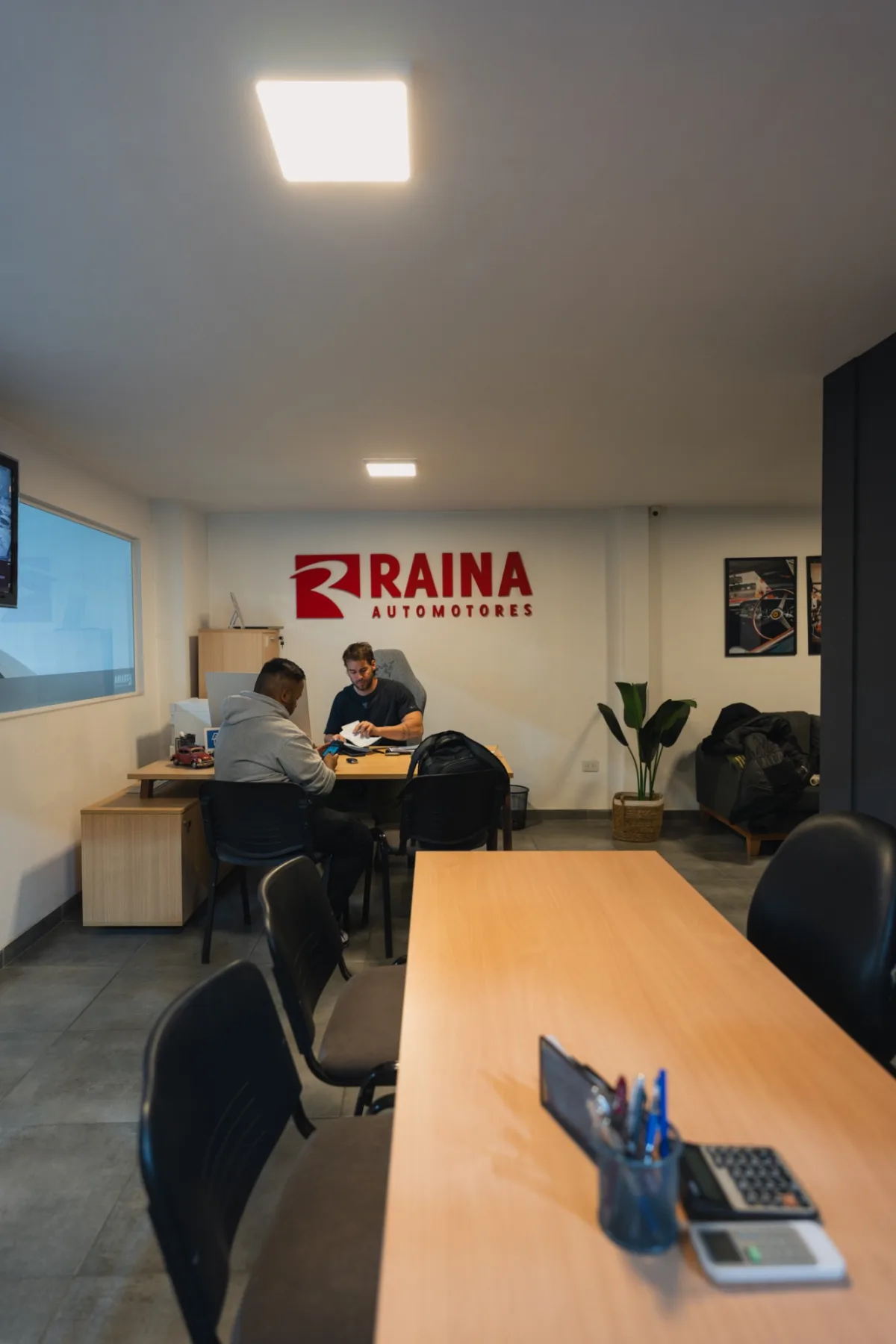 Oficina de atención de Raina Automotores con un asesor y un cliente revisando documentación