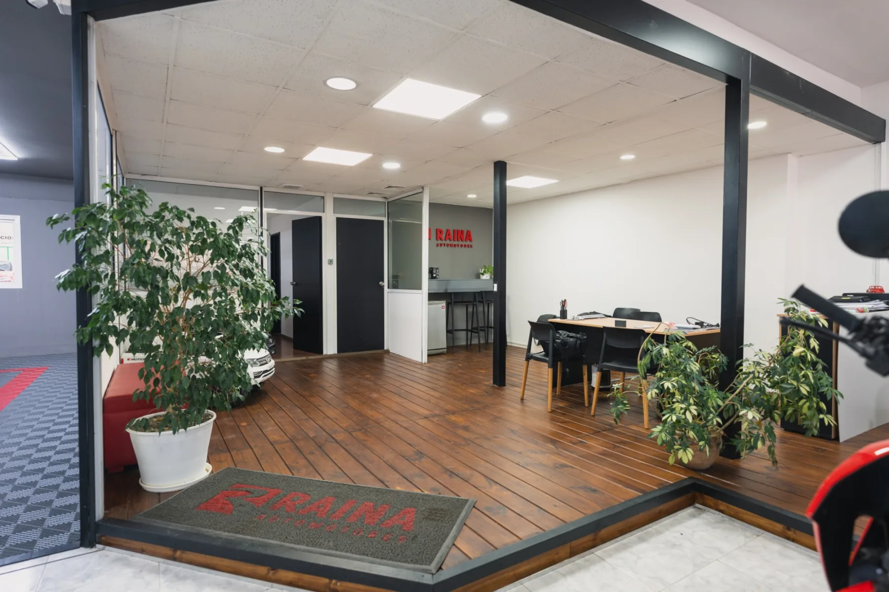 Recepción del salón de Raina Automotores con deck de madera y escritorio de atención